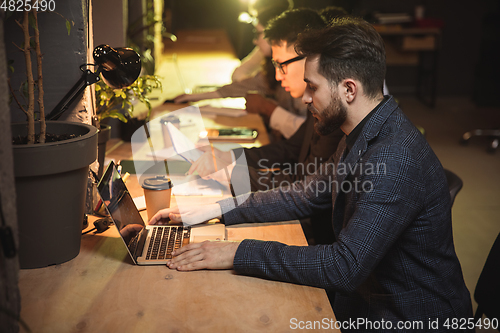 Image of Colleagues working together in modern office using devices and gadgets during creative meeting