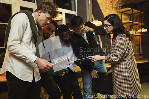 Image of Colleagues working together in modern office using devices and gadgets during creative meeting