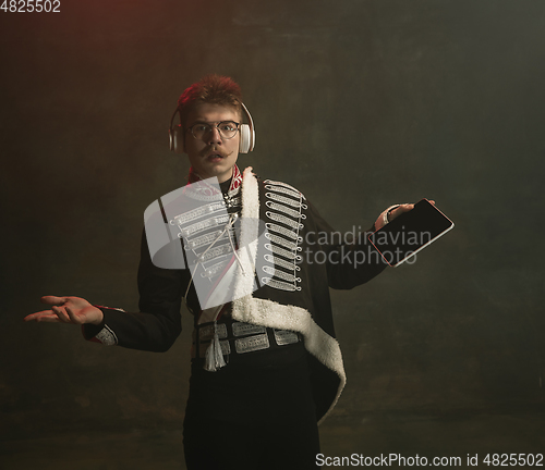 Image of Young man in suit as royal person isolated on dark green background. Retro style, comparison of eras concept. Beautiful male model like historical character, monarch, old-fashioned.