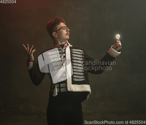 Image of Young man in suit as royal person isolated on dark green background. Retro style, comparison of eras concept. Beautiful male model like historical character, monarch, old-fashioned.