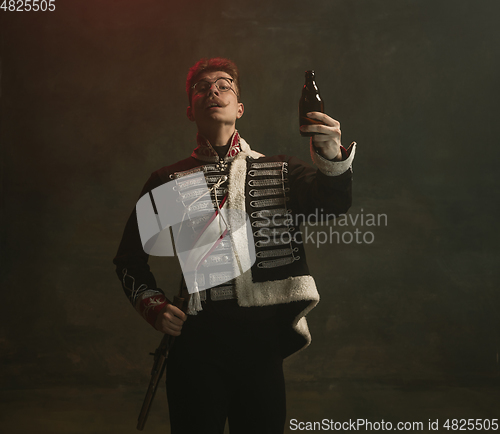 Image of Young man in suit as royal person isolated on dark green background. Retro style, comparison of eras concept. Beautiful male model like historical character, monarch, old-fashioned.