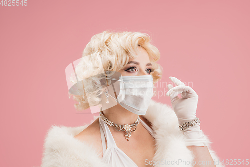 Image of Portrait of young woman in white dress on coral pink background. Female model as a legendary actress. Pin up. Concept of comparison of eras, modern, fashion, beauty.