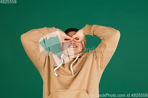 Image of Asian man\'s portrait isolated over green studio background with copyspace