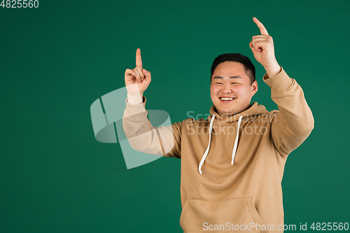 Image of Asian man\'s portrait isolated over green studio background with copyspace