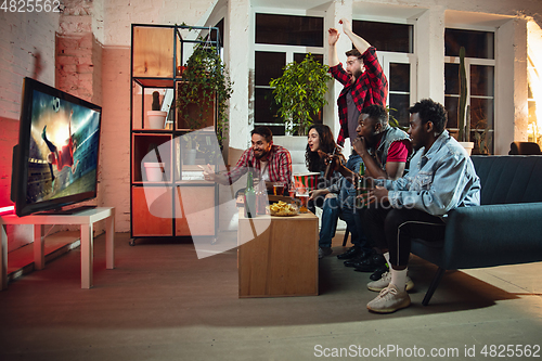 Image of Group of friends watching TV, sport match together. Emotional fans cheering for favourite team, watching on exciting game. Concept of friendship, leisure activity, emotions