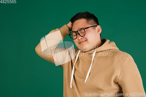 Image of Asian man\'s portrait isolated over green studio background with copyspace