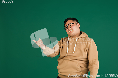 Image of Asian man\'s portrait isolated over green studio background with copyspace