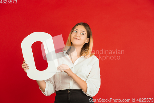 Image of Valentine\'s day celebration, happy caucasian girl holding letter on red background