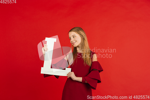 Image of Valentine\'s day celebration, happy caucasian girl holding letter on red background