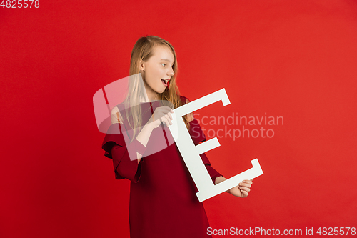 Image of Valentine\'s day celebration, happy caucasian girl holding letter on red background