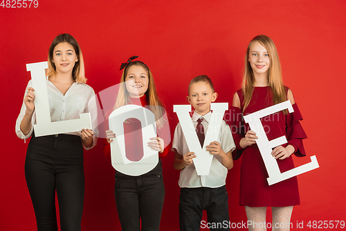 Image of Valentine\'s day celebration, happy caucasian teens holding letters on red background