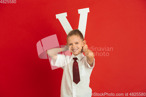 Image of Valentine\'s day celebration, happy caucasian boy holding letter on red background