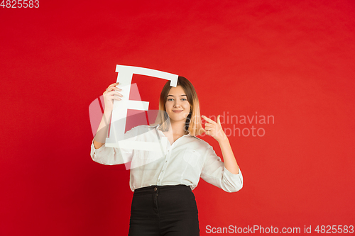 Image of Valentine\'s day celebration, happy caucasian girl holding letter on red background