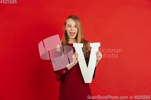 Image of Valentine\'s day celebration, happy caucasian girl holding letter on red background