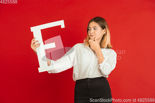 Image of Valentine\'s day celebration, happy caucasian girl holding letter on red background