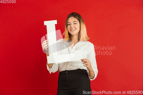 Image of Valentine\'s day celebration, happy caucasian girl holding letter on red background