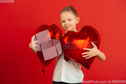 Image of Valentine\'s day celebration, happy caucasian boy isolated on red background