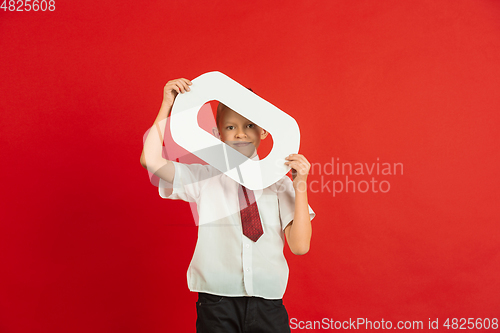 Image of Valentine\'s day celebration, happy caucasian boy holding letter on red background