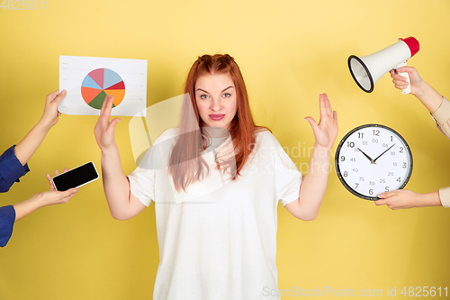 Image of Caucasian young woman\'s portrait on yellow background, too much tasks