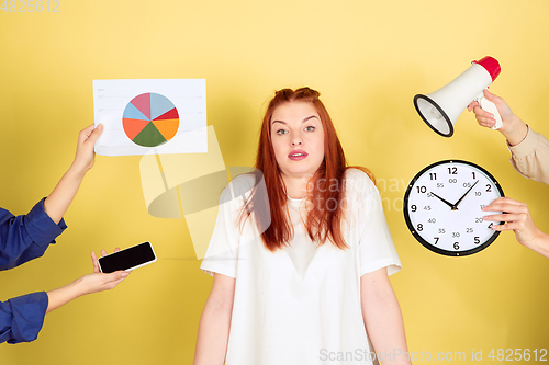 Image of Caucasian young woman\'s portrait on yellow background, too much tasks