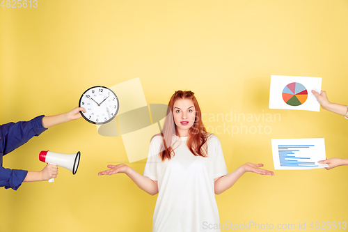 Image of Caucasian young woman\'s portrait on yellow background, too much tasks