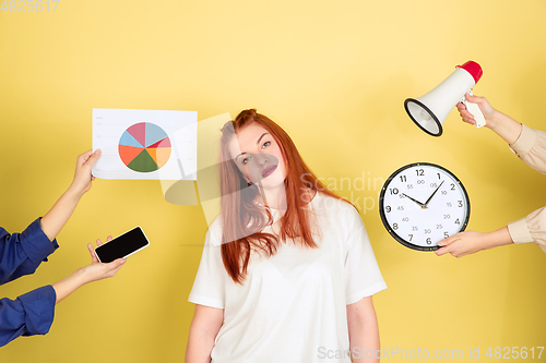 Image of Caucasian young woman\'s portrait on yellow background, too much tasks