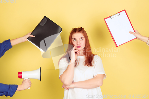 Image of Caucasian young woman\'s portrait on yellow background, too much tasks