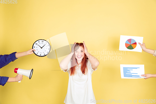 Image of Caucasian young woman\'s portrait on yellow background, too much tasks