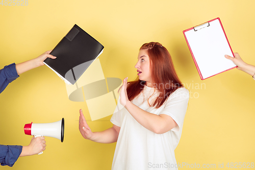 Image of Caucasian young woman\'s portrait on yellow background, too much tasks