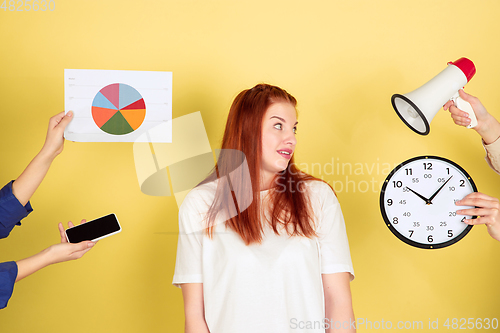 Image of Caucasian young woman\'s portrait on yellow background, too much tasks