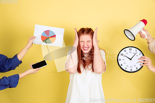 Image of Caucasian young woman\'s portrait on yellow background, too much tasks