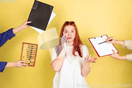 Image of Caucasian young woman\'s portrait on yellow background, too much tasks