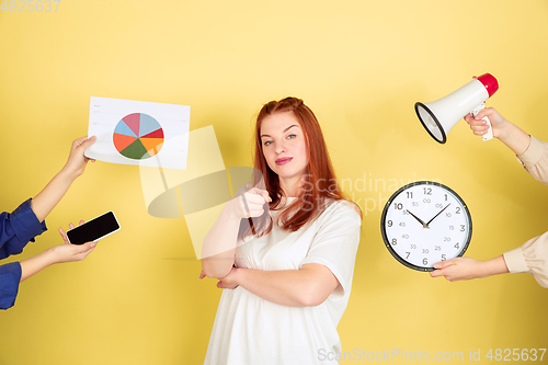 Image of Caucasian young woman\'s portrait on yellow background, too much tasks