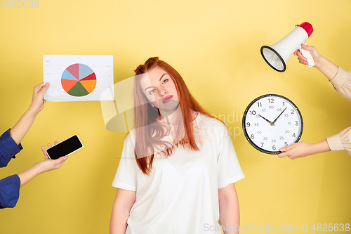 Image of Caucasian young woman\'s portrait on yellow background, too much tasks