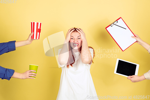 Image of Caucasian young woman\'s portrait on yellow background, too much tasks