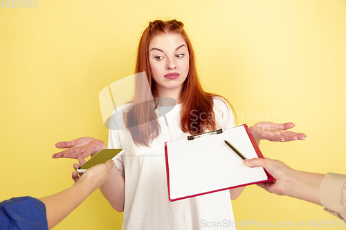 Image of Caucasian young woman\'s portrait on yellow background, too much tasks