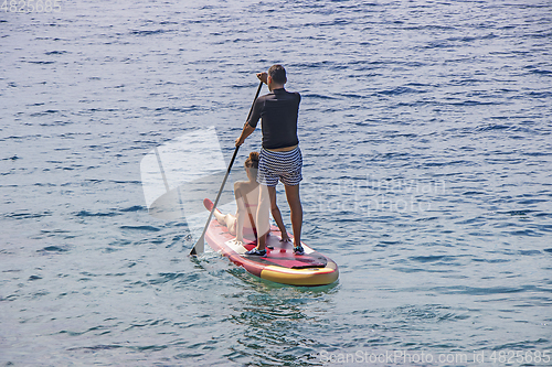 Image of Young couple on stand up paddleboard surfboard surfing together