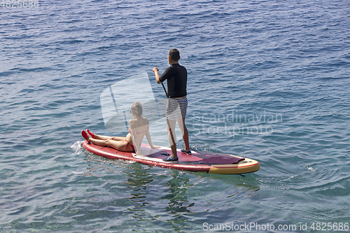 Image of Young couple on stand up paddleboard surfboard surfing together