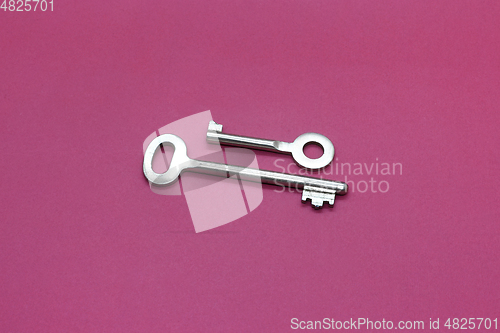 Image of Metal keys close-up on bright crimson paper