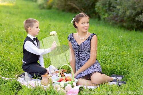 Image of Little boy and teen age girl having picnic outdoors