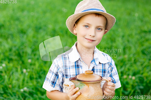 Image of handsome little boy with jug standing outdoors