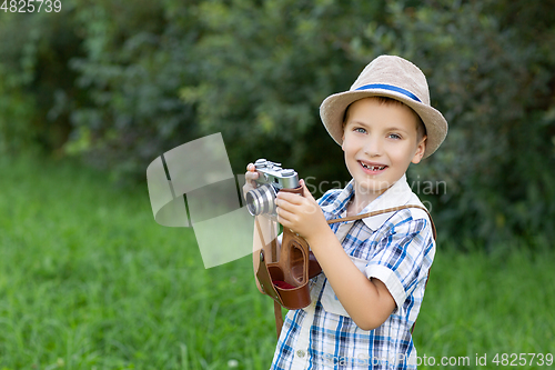 Image of handsome little boy with retro camera outdoors