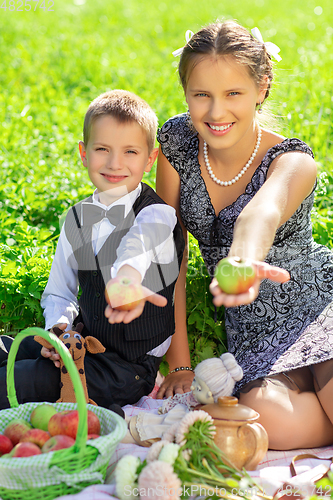 Image of Little boy and teen age girl having picnic outdoors