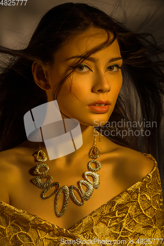 Image of beautiful young woman with necklace in golden light