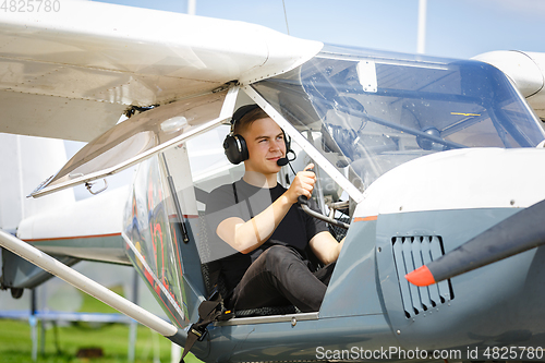 Image of outdoor shot of young man in small plane cockpit