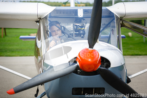 Image of outdoor shot of young man in small plane cockpit