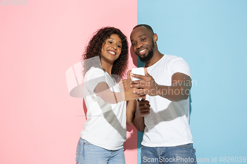 Image of Young emotional man and woman on pink and blue background