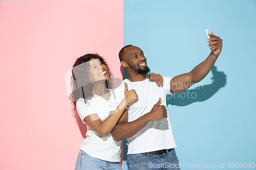 Image of Young emotional man and woman on pink and blue background