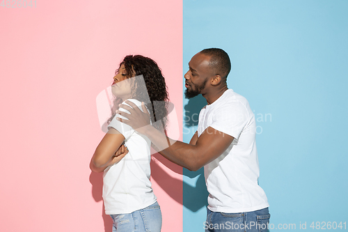 Image of Young emotional man and woman on pink and blue background