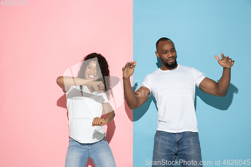 Image of Young emotional man and woman on pink and blue background